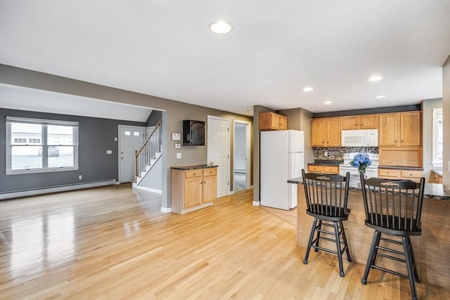 105 Edgewater Dr W, Falmouth, MA 02536 - kitchen with dark countertops, white appliances, a baseboard heating unit, light wood-style flooring, and a breakfast bar area