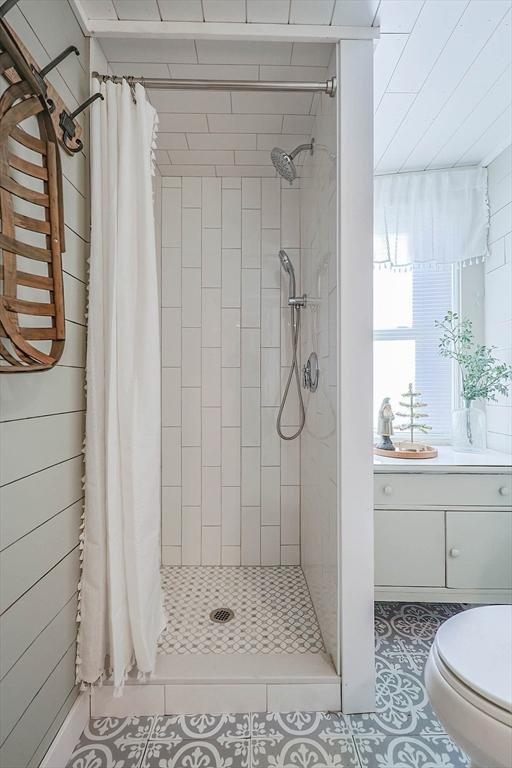 bathroom featuring a shower with shower curtain, tile patterned flooring, and toilet