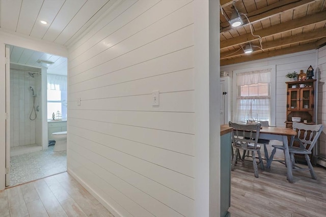 hall with beam ceiling, wood walls, wood ceiling, and light wood-type flooring