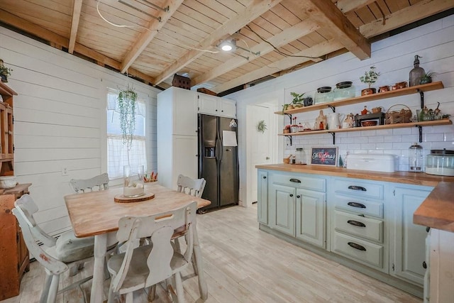 dining room with wood walls, beam ceiling, wood ceiling, and light hardwood / wood-style flooring