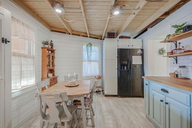 dining area featuring wood walls, light hardwood / wood-style flooring, and wooden ceiling