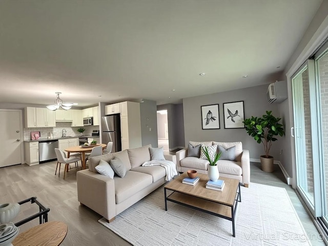 living room with a notable chandelier, light wood-type flooring, baseboards, a wall mounted AC, and recessed lighting