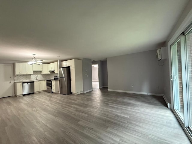unfurnished living room featuring a sink, an inviting chandelier, baseboards, and light wood finished floors