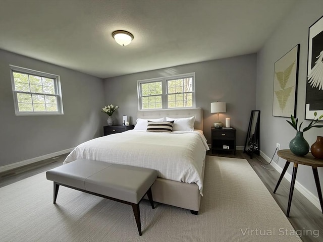 bedroom featuring baseboards, multiple windows, and wood finished floors