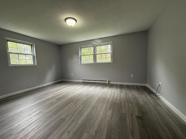 empty room featuring baseboards, a baseboard radiator, and dark wood-style floors