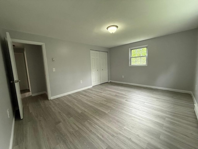 unfurnished bedroom with a closet, wood finished floors, and baseboards
