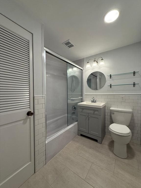 bathroom with toilet, combined bath / shower with glass door, visible vents, tile patterned flooring, and vanity