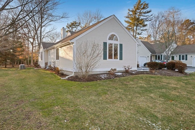 view of side of home with cooling unit, a lawn, and a garage