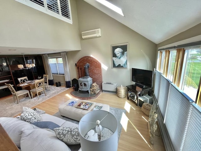 16 Howard Ave, Wells, ME 04090 - living room featuring a wall mounted air conditioner, a wood stove, wood finished floors, high vaulted ceiling, and baseboards