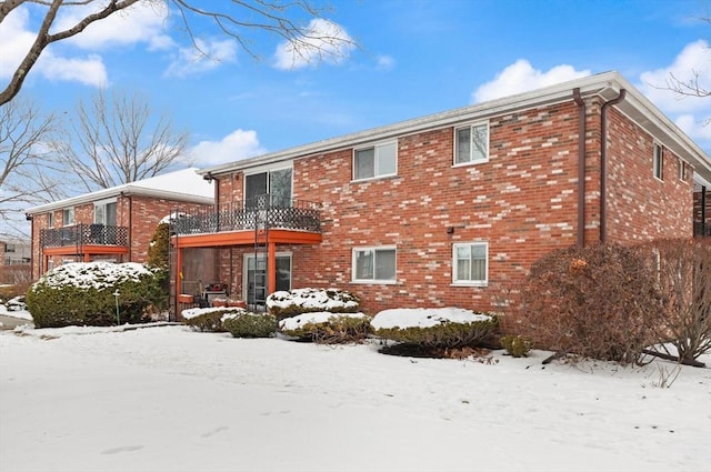 snow covered back of property featuring a balcony