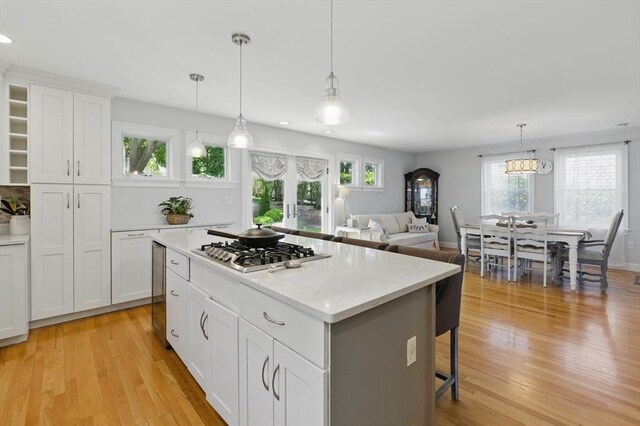 96 Sea Ave, Quincy, MA 02169 - kitchen featuring stainless steel gas cooktop, light wood-style floors, a kitchen island, white cabinets, and a breakfast bar area