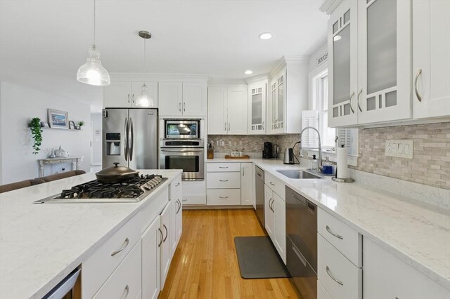 96 Sea Ave, Quincy, MA 02169 - kitchen with stainless steel appliances, a sink, hanging light fixtures, white cabinets, and light stone counters
