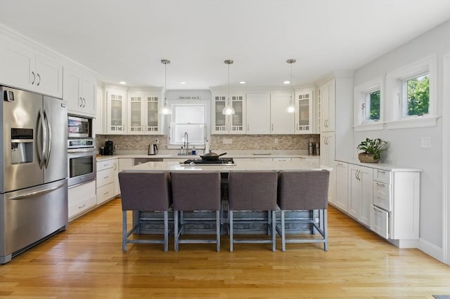 96 Sea Ave, Quincy, MA 02169 - kitchen featuring appliances with stainless steel finishes, a kitchen breakfast bar, a sink, white cabinets, and tasteful backsplash