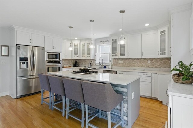 96 Sea Ave, Quincy, MA 02169 - kitchen with appliances with stainless steel finishes, a breakfast bar area, a kitchen island, white cabinets, and recessed lighting