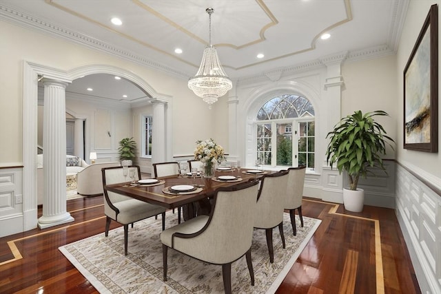 dining room featuring ornate columns, dark wood-type flooring, a notable chandelier, and ornamental molding