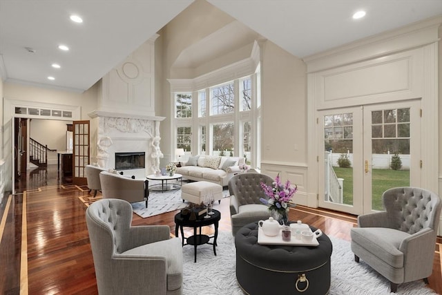 living room with a premium fireplace, hardwood / wood-style floors, a high ceiling, and ornamental molding