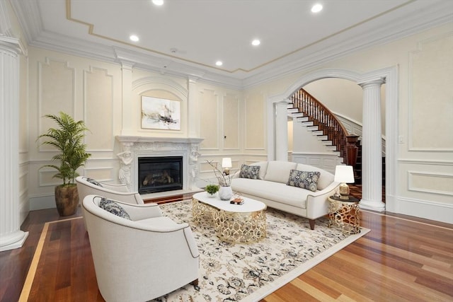 living room featuring hardwood / wood-style flooring, ornate columns, crown molding, and a high end fireplace