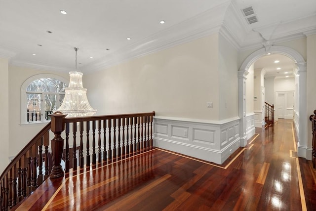 hall with dark hardwood / wood-style flooring, ornamental molding, and an inviting chandelier