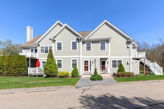 view of front of property featuring stairway, a front lawn, and a chimney