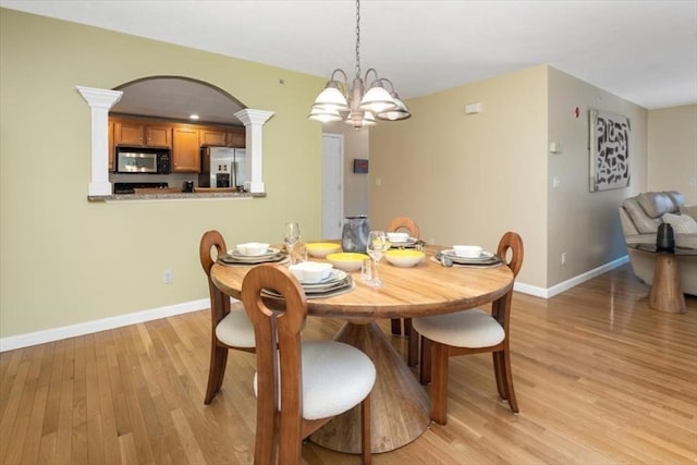 dining space with an inviting chandelier, baseboards, light wood-type flooring, and ornate columns