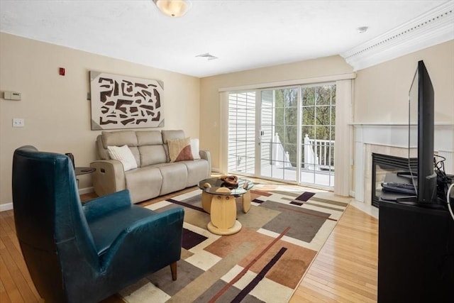 living area with wood-type flooring, a fireplace with flush hearth, and visible vents