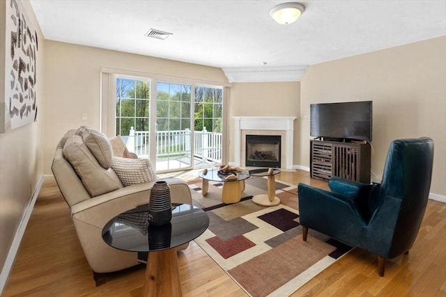 living room with baseboards, a fireplace, wood finished floors, and visible vents