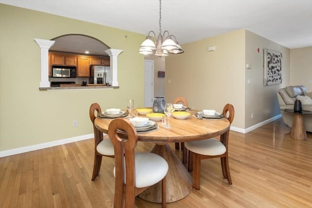 dining area with a chandelier, baseboards, decorative columns, and light wood-style floors