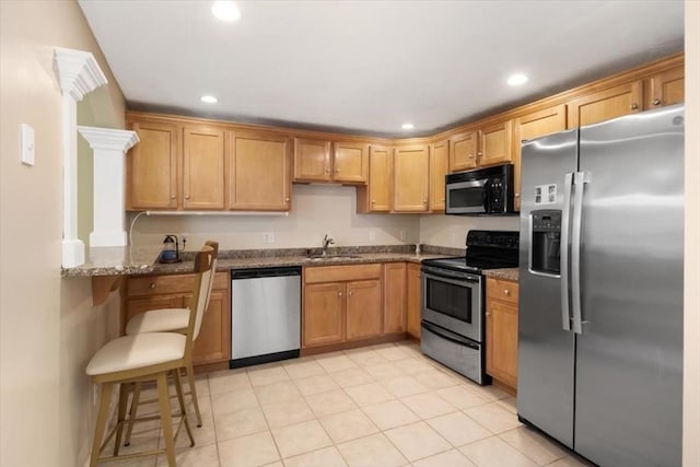kitchen with recessed lighting, appliances with stainless steel finishes, a sink, and dark stone countertops
