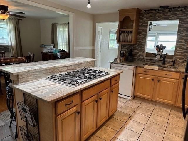 kitchen featuring stainless steel gas cooktop, a center island, dishwasher, and sink