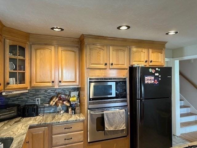 kitchen with tasteful backsplash, light stone countertops, and stainless steel appliances