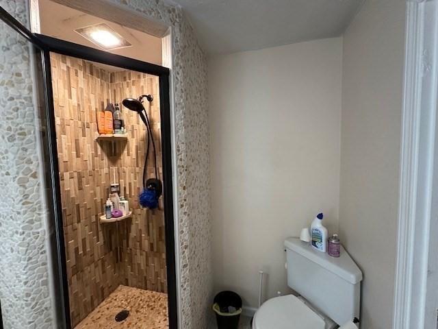 bathroom featuring tiled shower and toilet