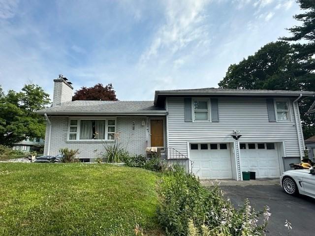 split level home with a garage and a front lawn