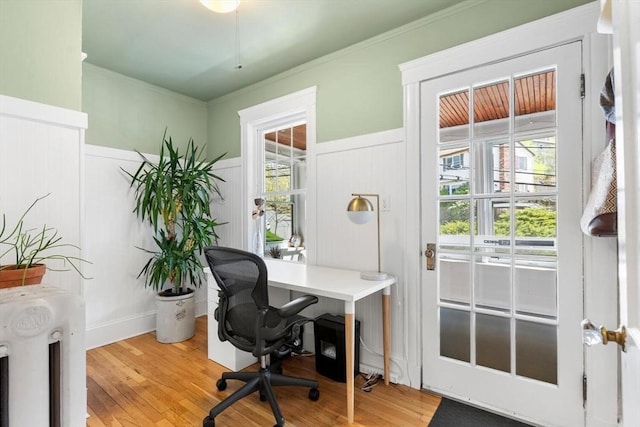 office area with a decorative wall, light wood finished floors, and a wainscoted wall
