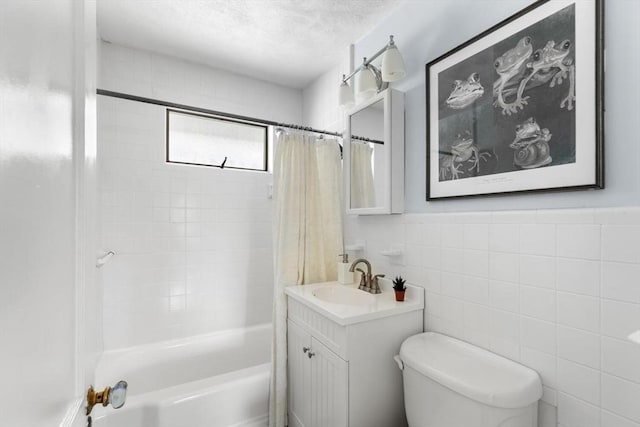 full bathroom featuring vanity, shower / tub combo with curtain, toilet, a textured ceiling, and tile walls