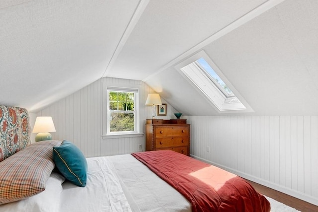 bedroom with baseboards, wood finished floors, and lofted ceiling with skylight