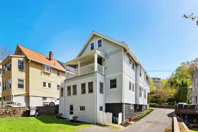 back of house with a lawn and a balcony