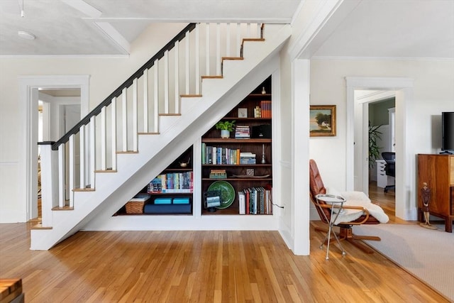 stairway featuring wood-type flooring and ornamental molding