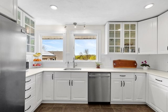 kitchen with appliances with stainless steel finishes, a sink, white cabinetry, recessed lighting, and glass insert cabinets
