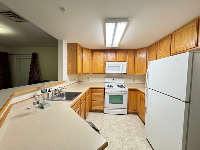 kitchen with kitchen peninsula, white appliances, and sink