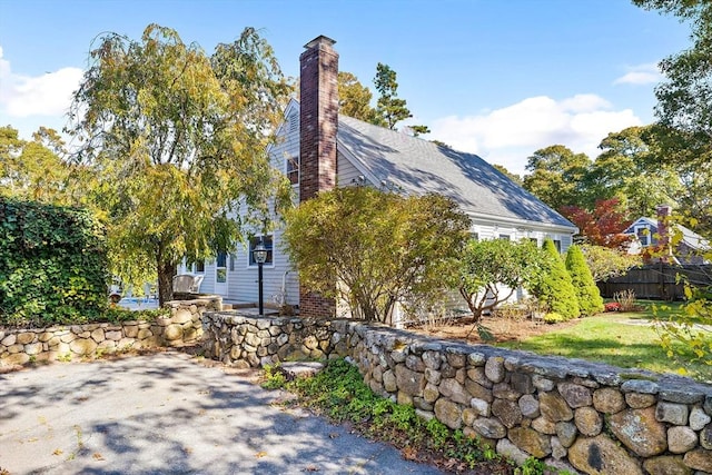 view of side of home with a chimney and fence