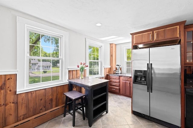 553 Center St, Hanover, MA 02339 - kitchen with stainless steel refrigerator with ice dispenser, baseboard heating, a wainscoted wall, light tile patterned floors, and wood walls