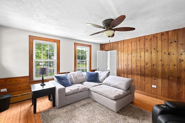 553 Center St, Hanover, MA 02339 - living room with wooden walls, light wood finished floors, a baseboard heating unit, and ceiling fan