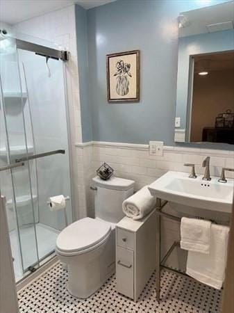 bathroom featuring walk in shower, toilet, tile walls, and sink