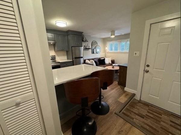 kitchen featuring ceiling fan, dark hardwood / wood-style flooring, a kitchen bar, gray cabinets, and appliances with stainless steel finishes