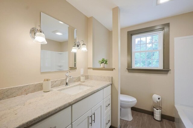 649 S Main St, Raynham, MA 02767 - bathroom featuring wood finished floors, toilet, vanity, a bathtub, and baseboards