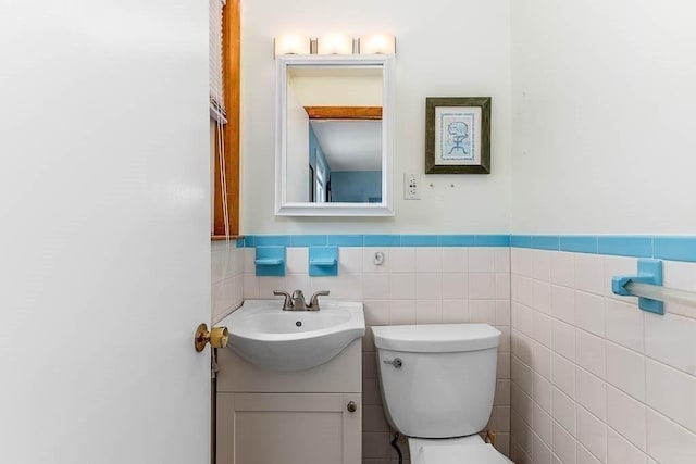 bathroom with tile walls, toilet, and vanity