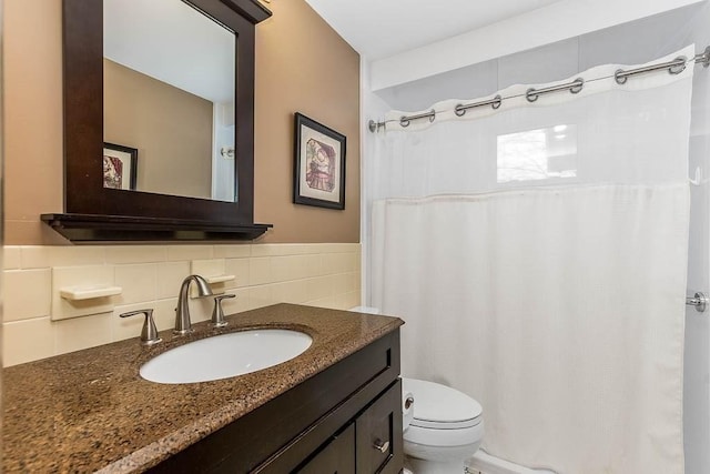 bathroom with toilet, tile walls, and vanity