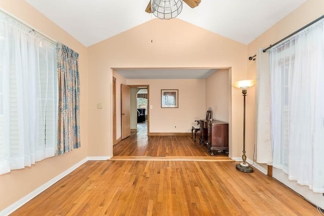 corridor with light hardwood / wood-style floors and vaulted ceiling