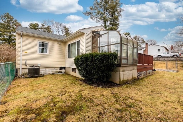 rear view of house featuring central AC and a yard