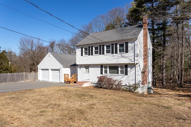 colonial inspired home featuring fence, a shingled roof, a chimney, concrete driveway, and a front lawn